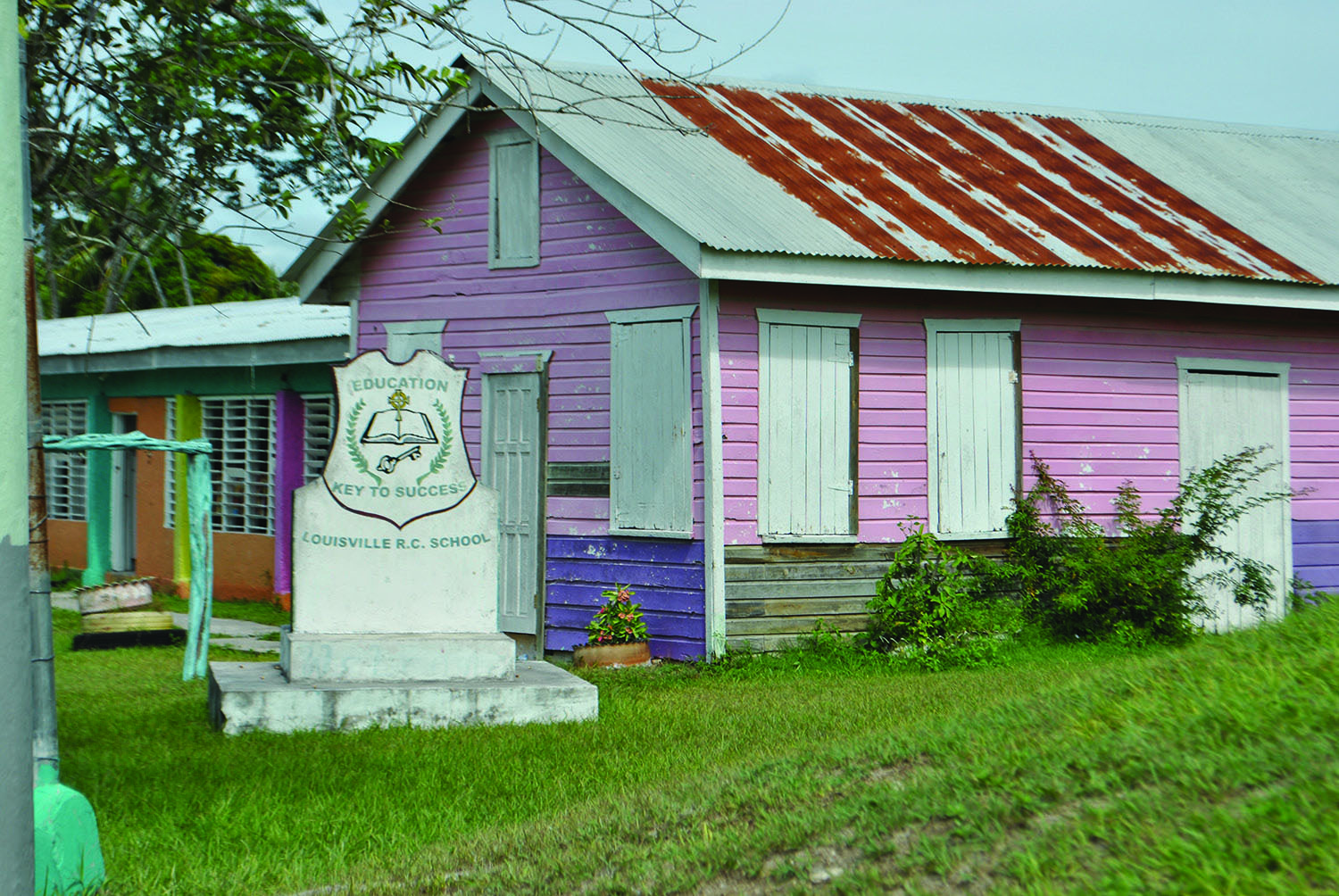 Pink school building with sign that reads "Education Key To Success Louisville R.C. School"