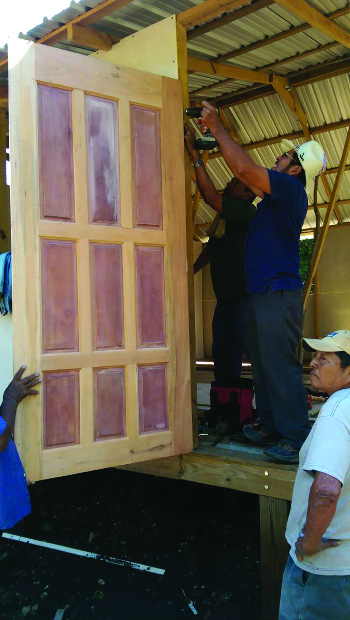 Multiple men working on installing a door to a building