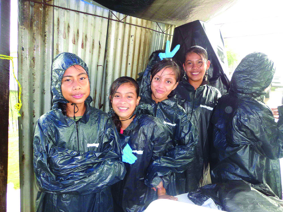 Five stuedents in raincoats taking shelter from rain