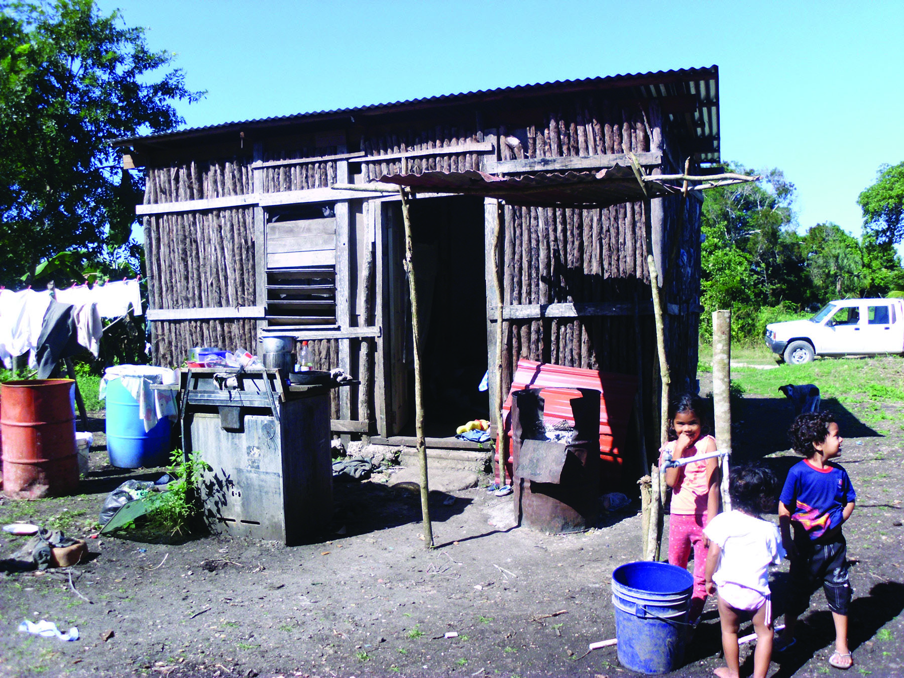 Three kids outside of a wooden shed